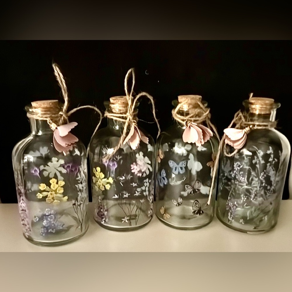 4 painted, glass bottle with cork stoppers. 5.5” flowers and butterflies.